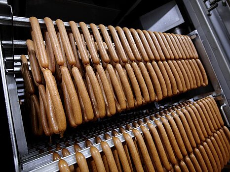 grand support métallique sur lequel sont suspendues de nombreuses saucisses, destinées à être cuites ou fumées