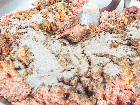 Photo d’un mélangeur contenant de la viande et plusieurs épices, illustrant le processus de préparation de la saumure et de mixage