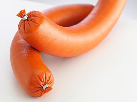 Image d’une saucisse avec des clips métalliques attachés à chaque bout, sur un fond simple.