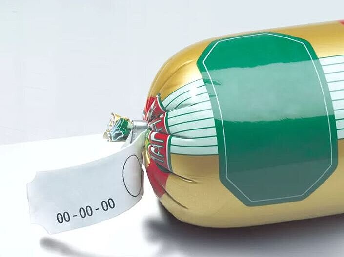 Image d’une saucisse avec des clips métalliques attachés à chaque bout, sur un fond simple.