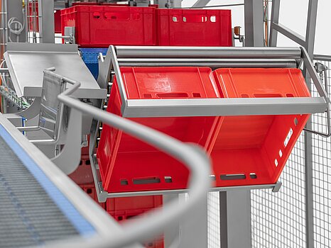 Photo montrant des bacs rouges en train d’être basculés par un système mécanique pour vider leur marchandise