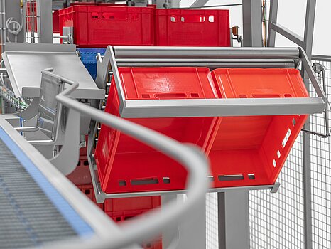 Photo montrant des bacs rouges en train d’être basculés par un système mécanique pour vider leur marchandise