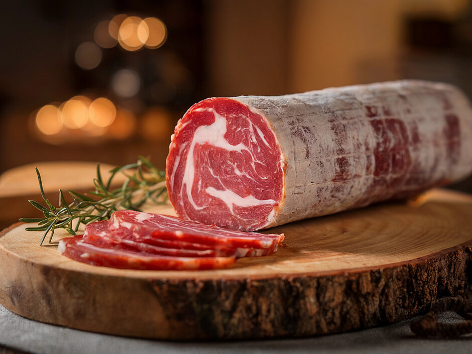 Photo d'une coppa à moitié coupée et quelques tranches fines sur une planche de bois Photo d'une coppa à moitié coupée et quelques tranches fines sur une planche de bois